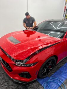 Aplicação de PPF no capô de Ford Mustang vermelho em Santa Felicidade, Curitiba.